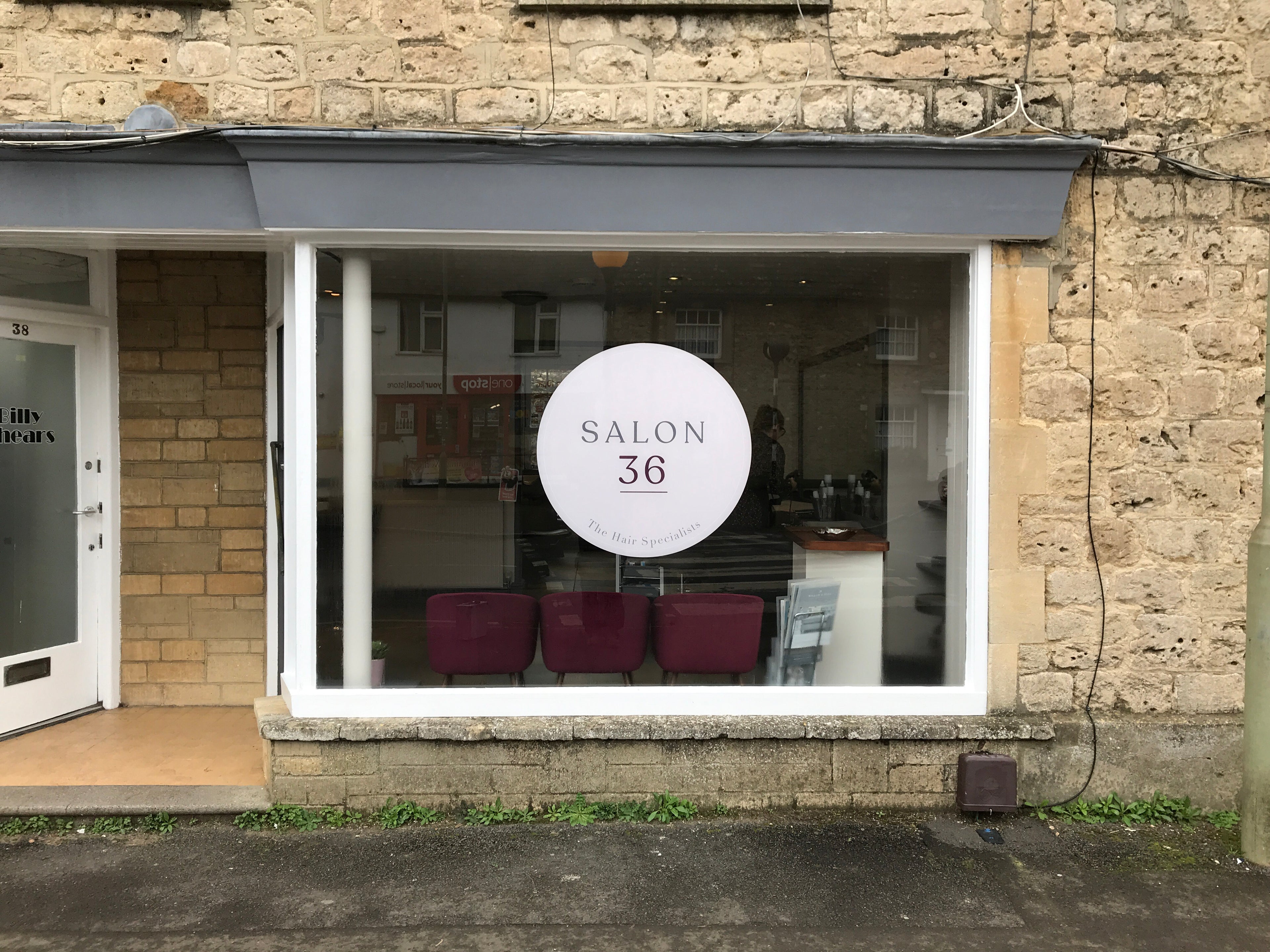 Glass door with a sign reading 'SALON 36' on a stone building.