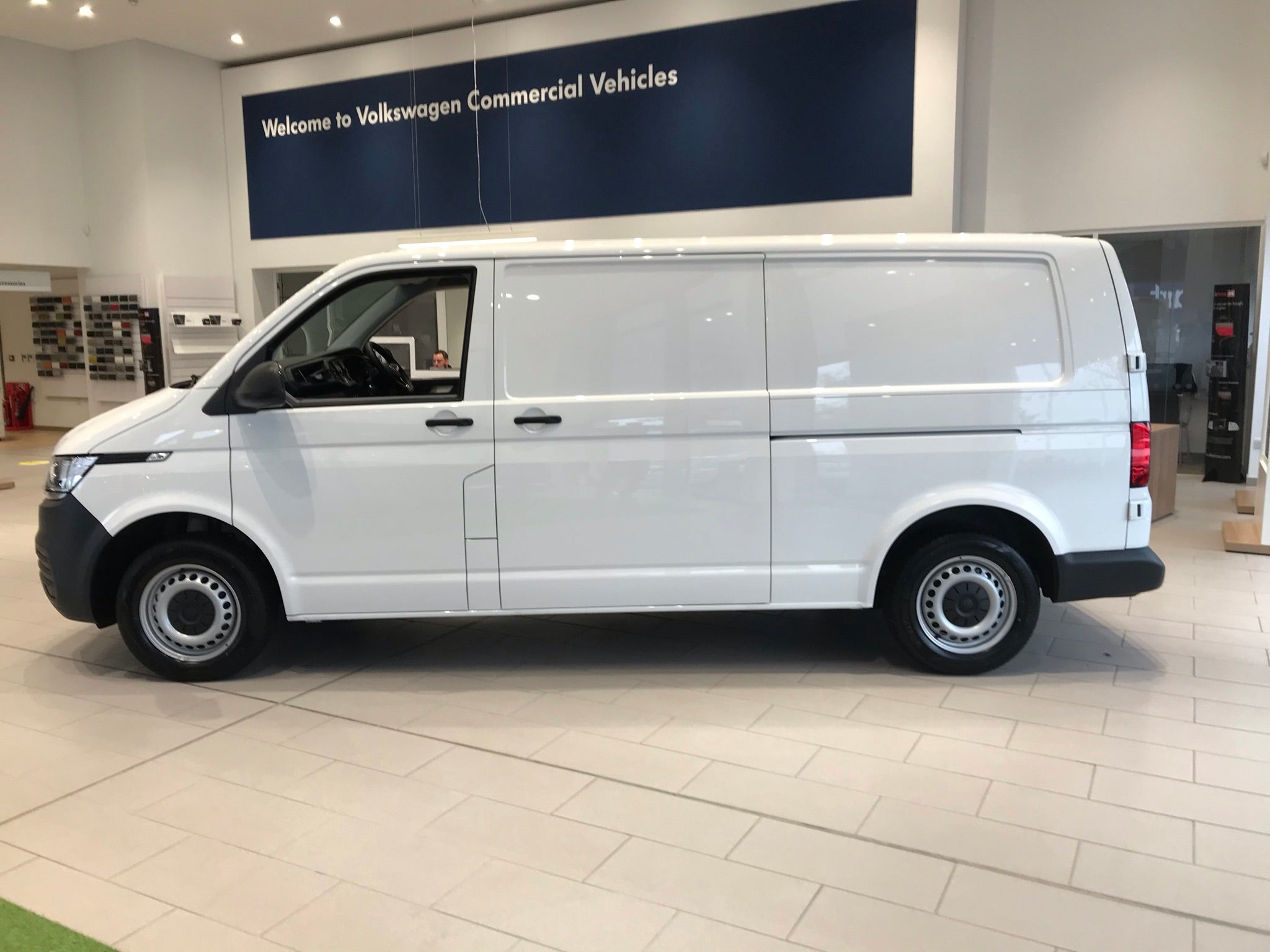 White van in a showroom with Volkswagen Commercial Vehicles sign.